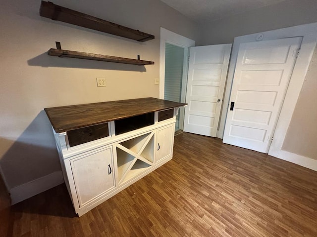 unfurnished dining area with baseboards and dark wood finished floors