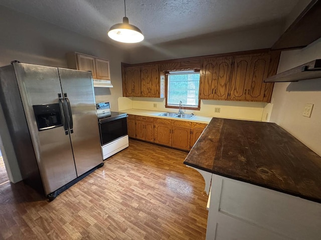 kitchen with light wood finished floors, under cabinet range hood, stainless steel fridge with ice dispenser, electric stove, and a sink