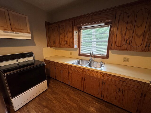 kitchen with a sink, range with electric stovetop, light countertops, dark wood finished floors, and under cabinet range hood