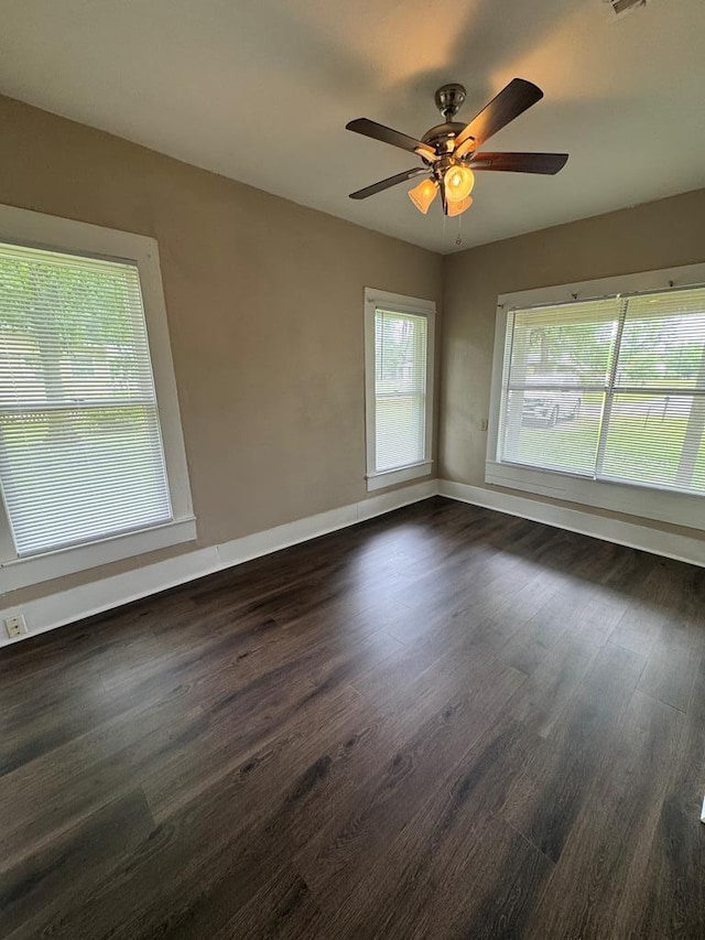 empty room featuring dark wood finished floors, baseboards, and a ceiling fan