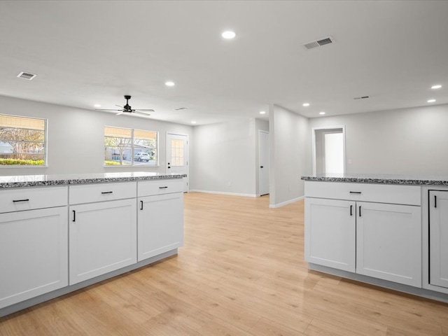 kitchen featuring white cabinetry, ceiling fan, stone countertops, and light wood-type flooring