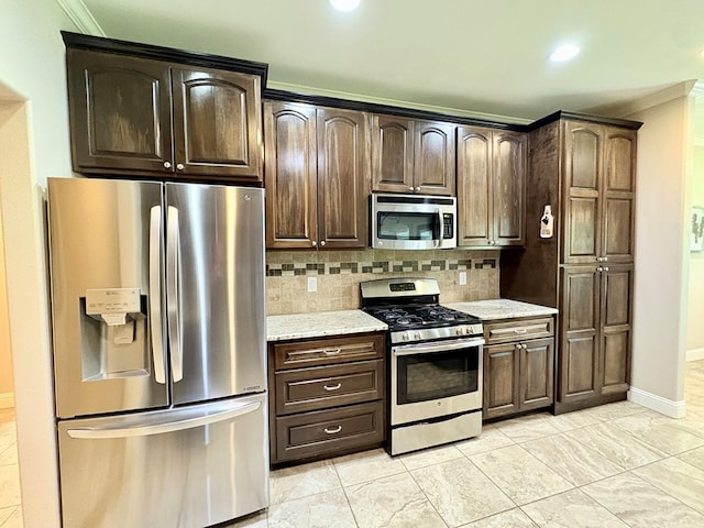 300 Deer Trace Blvd, Diboll, TX 75941 - kitchen with stainless steel appliances, decorative backsplash, crown molding, dark brown cabinetry, and light stone counters