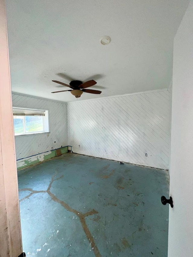 spare room with ceiling fan and wooden walls