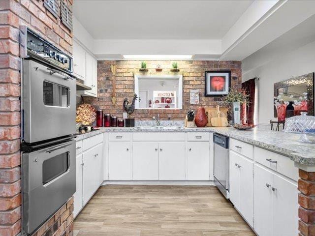 kitchen featuring kitchen peninsula, appliances with stainless steel finishes, white cabinets, and sink