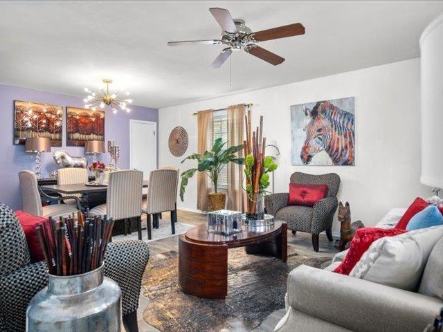 living room featuring ceiling fan with notable chandelier