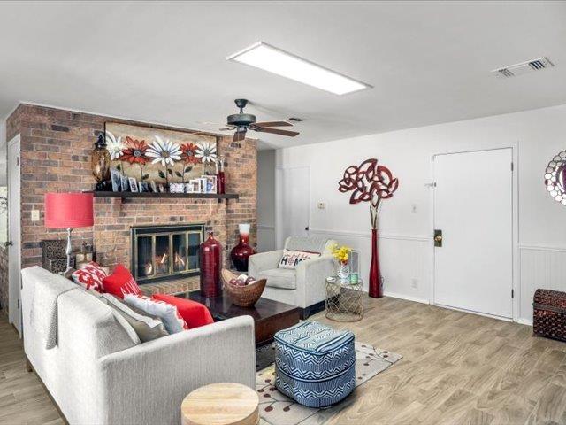 living room with hardwood / wood-style flooring, ceiling fan, and a fireplace