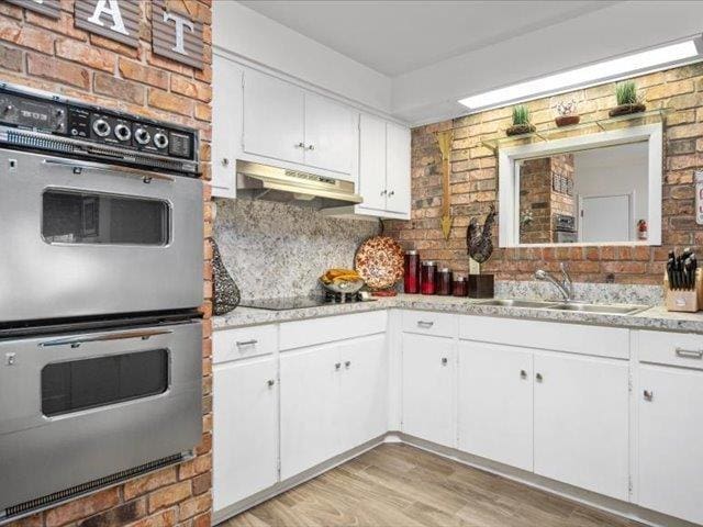 kitchen featuring white cabinetry, double oven, and sink