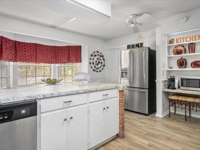 kitchen with ceiling fan, light stone countertops, light hardwood / wood-style flooring, white cabinets, and appliances with stainless steel finishes