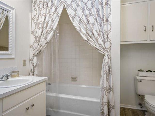 full bathroom featuring hardwood / wood-style floors, vanity, shower / bath combo, and toilet