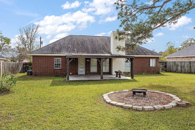 back of property with a yard, a fire pit, and a patio area