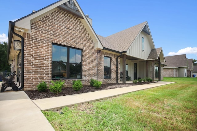 exterior space featuring a chimney, board and batten siding, a yard, and brick siding