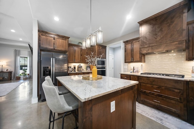 kitchen featuring stainless steel appliances, light stone countertops, tasteful backsplash, and a center island