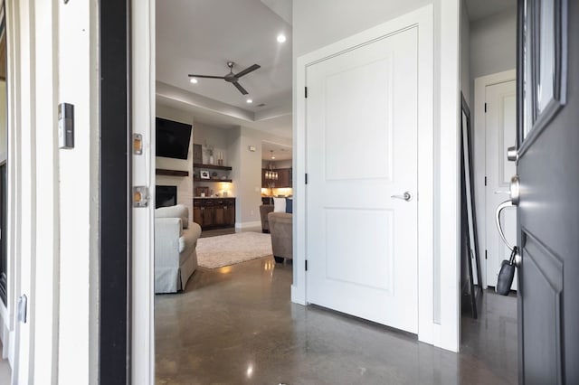 hall with baseboards, concrete flooring, recessed lighting, and a raised ceiling