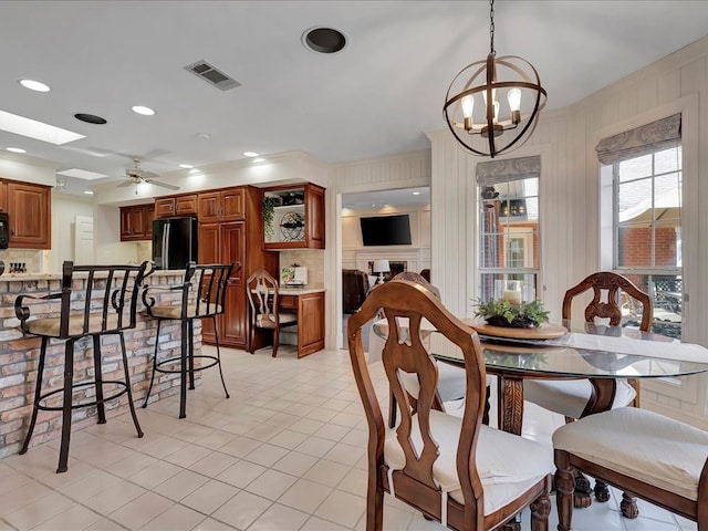 tiled dining area featuring a skylight and ceiling fan with notable chandelier