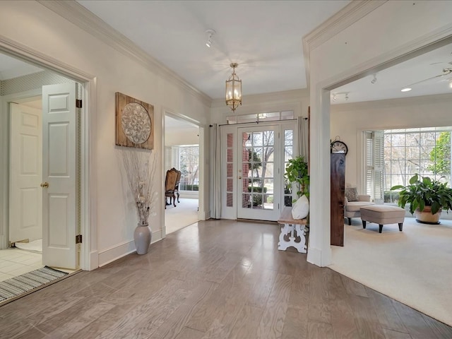 entrance foyer featuring wood-type flooring, ornamental molding, and a notable chandelier