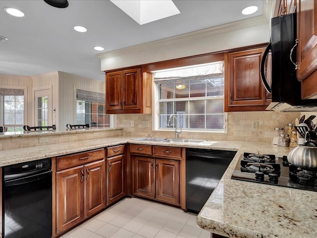 kitchen featuring tasteful backsplash, light stone counters, sink, black appliances, and light tile patterned floors