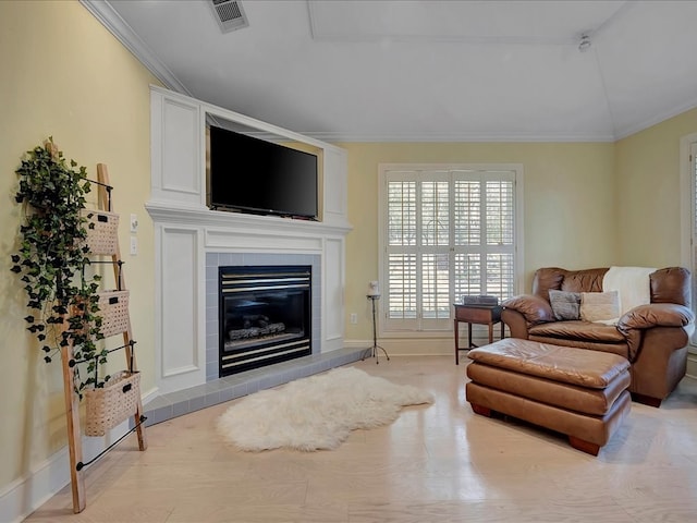 living room with ornamental molding and a tiled fireplace