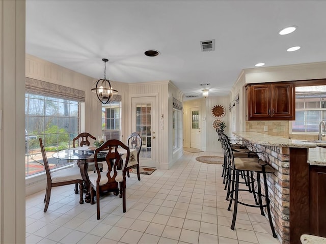 dining space with a chandelier, crown molding, and sink