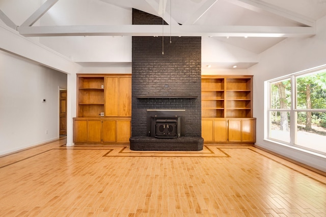 unfurnished living room featuring vaulted ceiling with beams, light wood-type flooring, and a wood stove