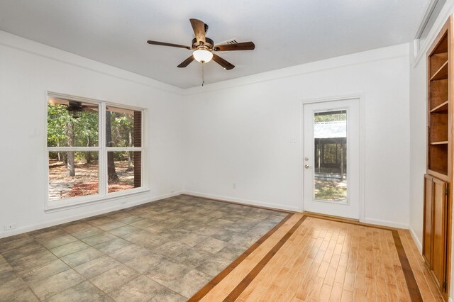 unfurnished room featuring wood-type flooring, ceiling fan, and built in shelves