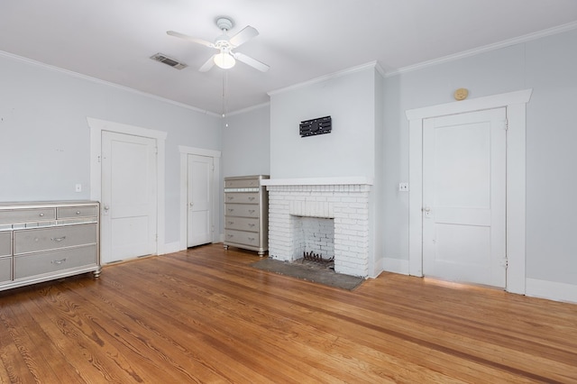 unfurnished living room featuring a fireplace, visible vents, ornamental molding, a ceiling fan, and wood finished floors