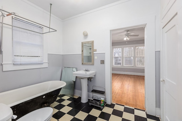 full bathroom with a ceiling fan, toilet, tile patterned floors, crown molding, and a freestanding tub