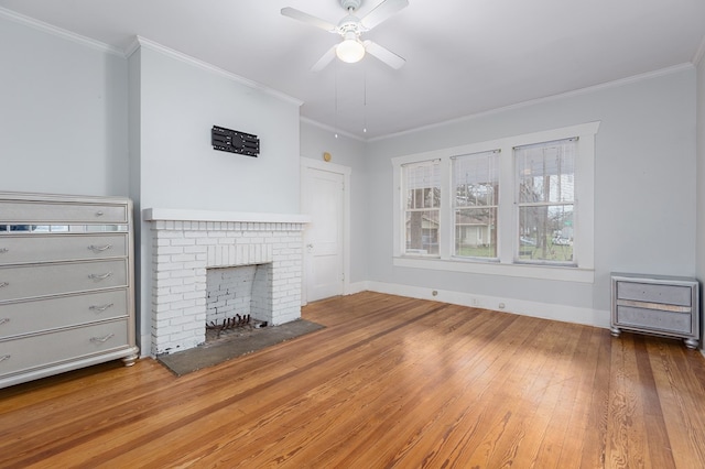 unfurnished living room featuring baseboards, a brick fireplace, wood finished floors, and crown molding