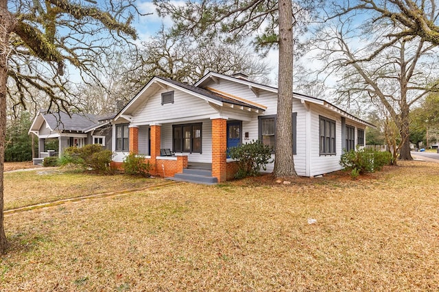 view of front facade featuring covered porch, brick siding, and a front yard