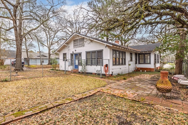 view of front of home featuring fence private yard, a patio area, and a chimney