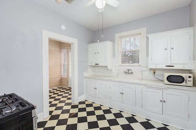 kitchen with dark floors, white cabinets, a sink, and light countertops