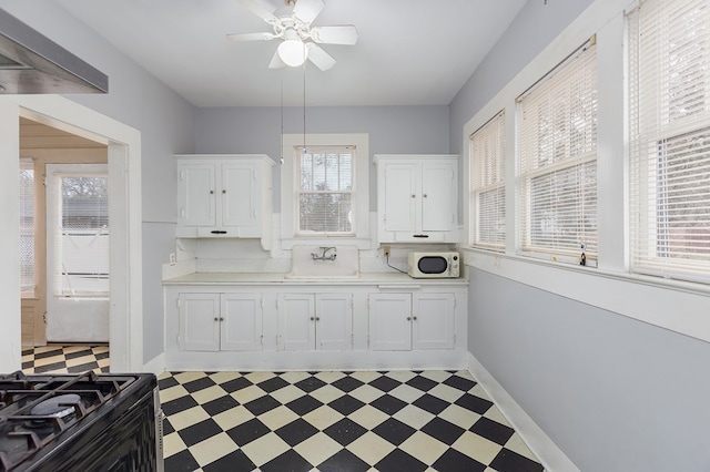 kitchen with dark floors, light countertops, white microwave, white cabinets, and a sink