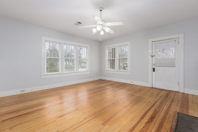 interior space featuring baseboards, visible vents, a ceiling fan, and light wood-style floors