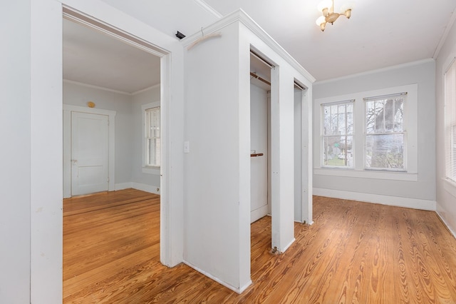 corridor with light wood finished floors, baseboards, and ornamental molding