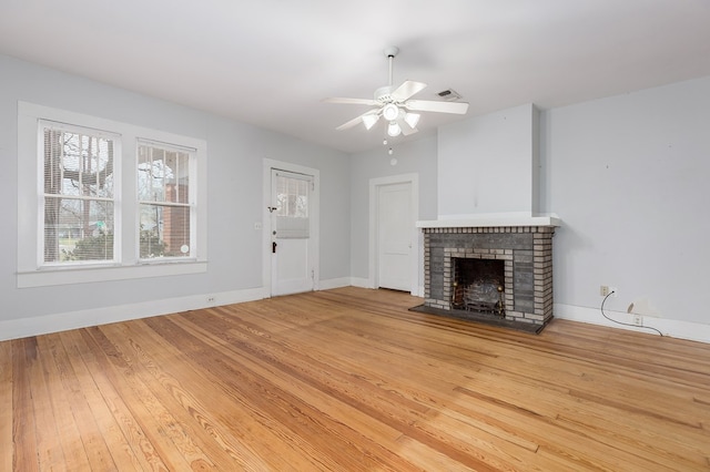 unfurnished living room with baseboards, a fireplace, a ceiling fan, and wood finished floors