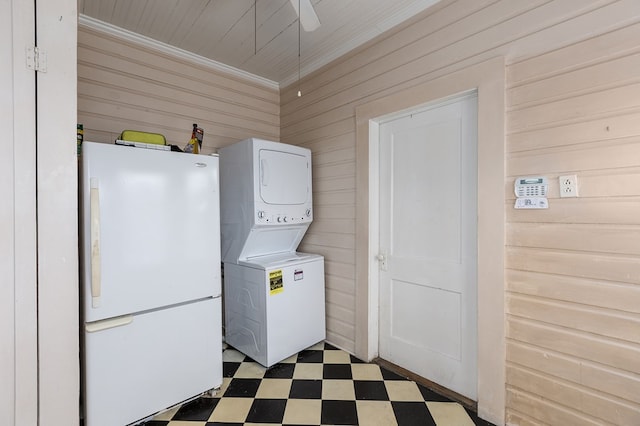 washroom with dark floors, laundry area, wood walls, stacked washer / dryer, and crown molding