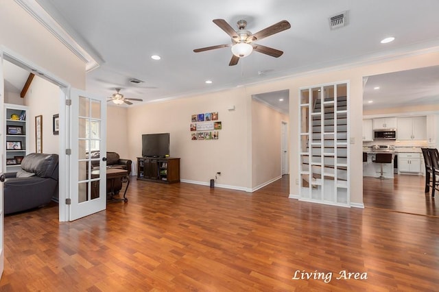 living area with visible vents, ceiling fan, crown molding, wood finished floors, and french doors