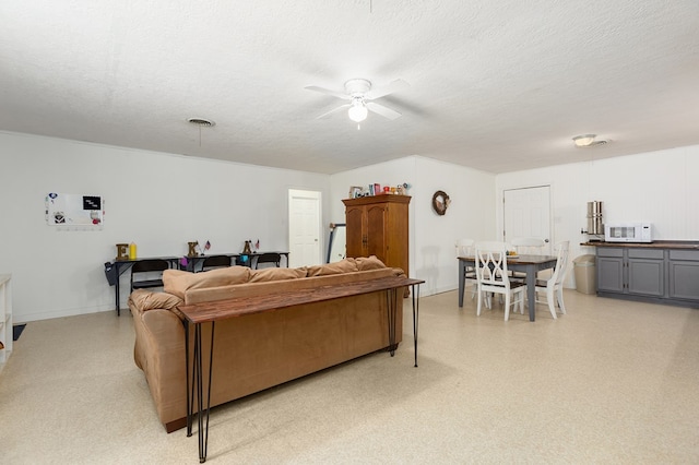 living room featuring ceiling fan and a textured ceiling