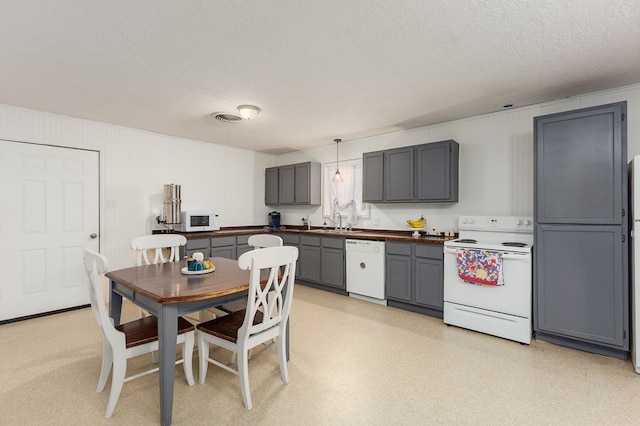 kitchen with a textured ceiling, gray cabinets, decorative light fixtures, and white appliances