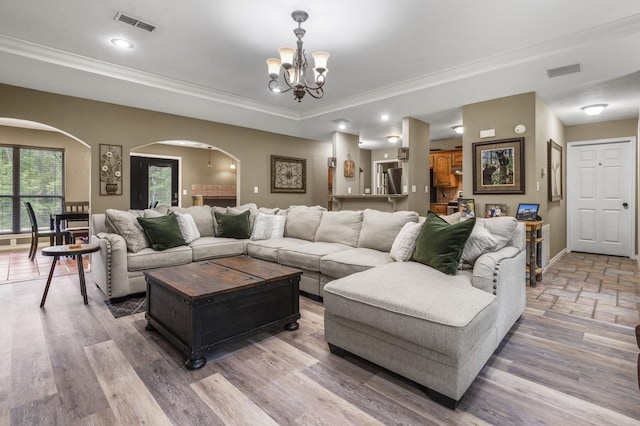 living room with hardwood / wood-style flooring, crown molding, and a notable chandelier