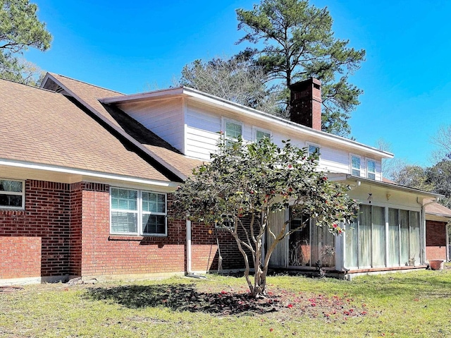 rear view of property featuring a sunroom and a yard