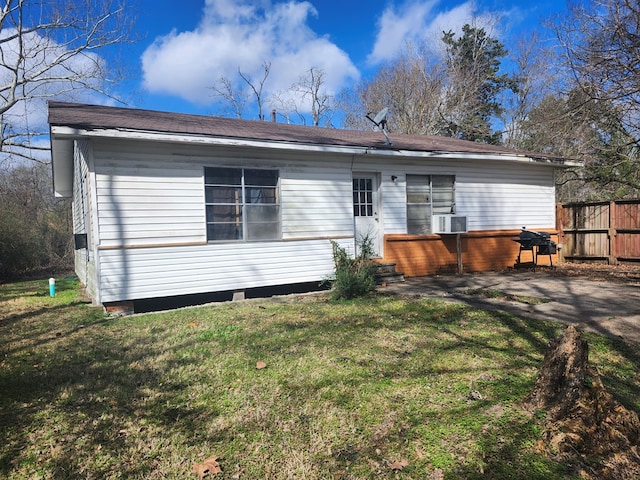 back of property featuring cooling unit, fence, and a lawn