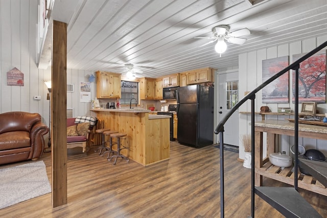 kitchen featuring kitchen peninsula, light brown cabinets, black appliances, and hardwood / wood-style flooring