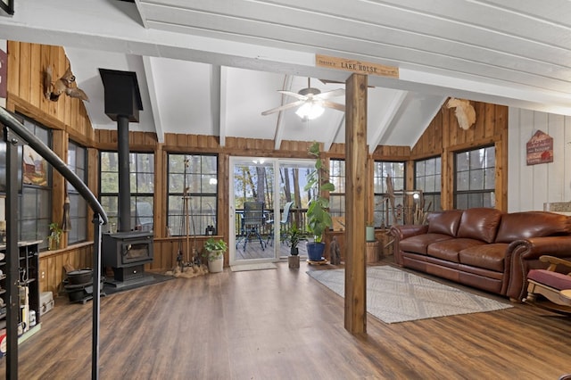 living room featuring a wood stove, wood walls, hardwood / wood-style floors, and ceiling fan