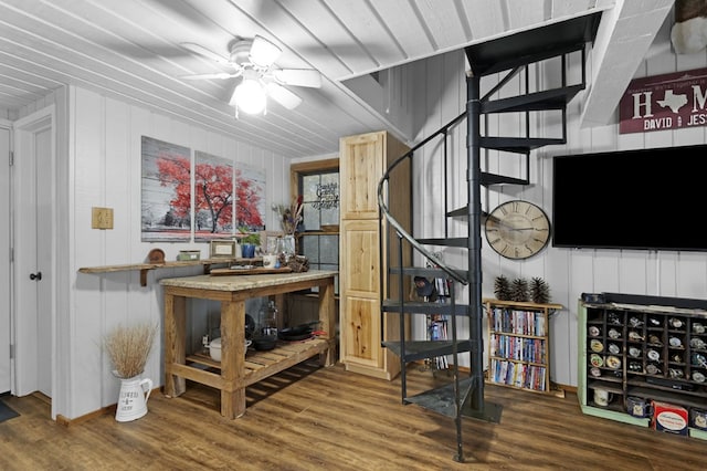 interior space featuring wood-type flooring, ceiling fan, and wood walls