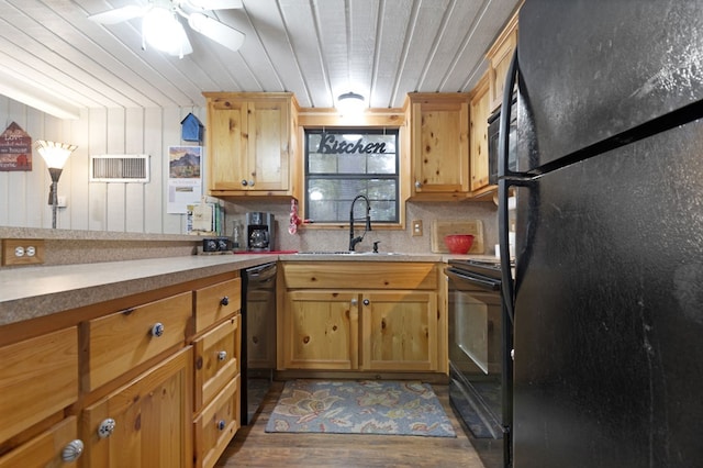 kitchen featuring wood walls, black appliances, sink, ceiling fan, and wood-type flooring