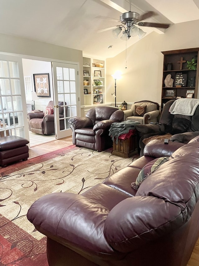 living room with built in shelves, ceiling fan, and vaulted ceiling