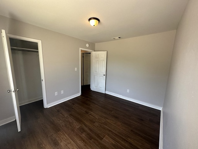 unfurnished bedroom with dark hardwood / wood-style floors and a closet