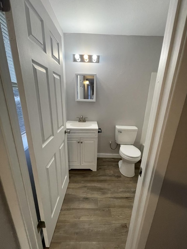 bathroom with wood-type flooring, vanity, and toilet