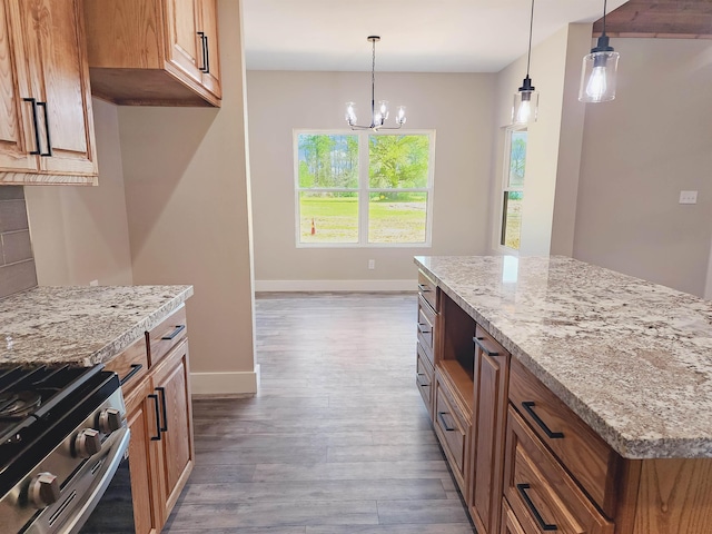 kitchen with hanging light fixtures, light hardwood / wood-style flooring, light stone countertops, stainless steel range oven, and a chandelier