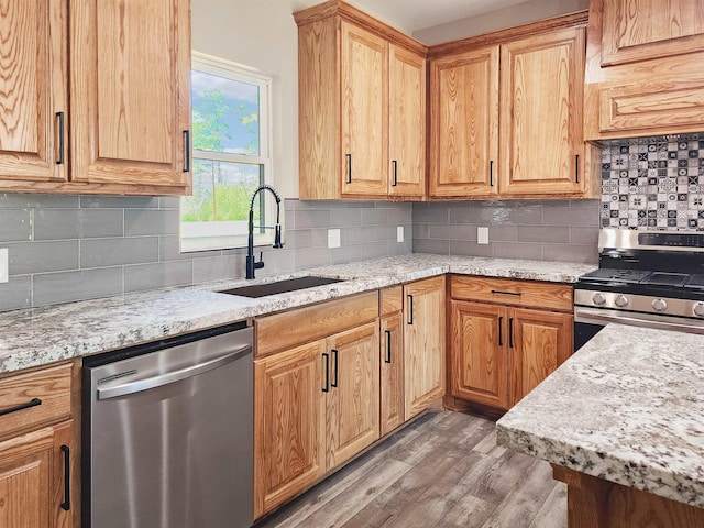 kitchen with sink, wood-type flooring, stainless steel appliances, and tasteful backsplash